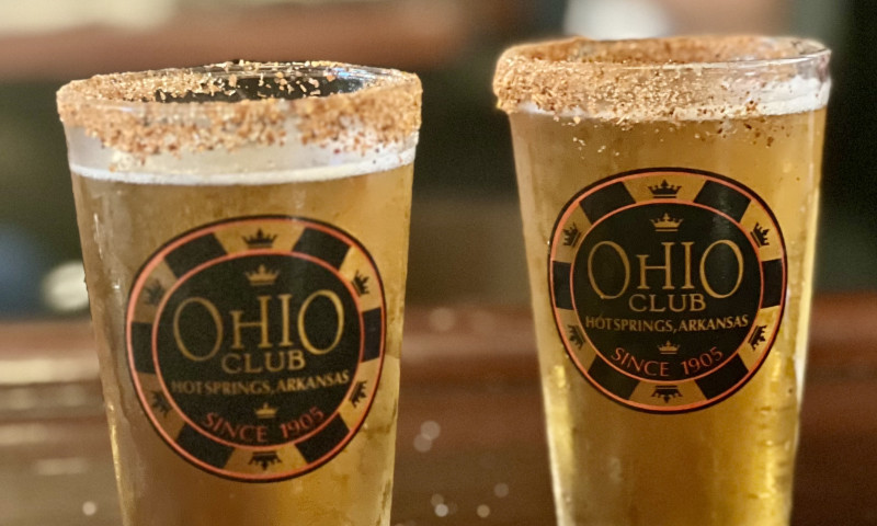 Two pint glasses filled with beer sit on a bar. 