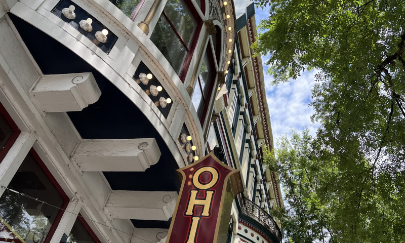 Looking up at victorian era commercial building with large red and yellow Ohio Club sign.