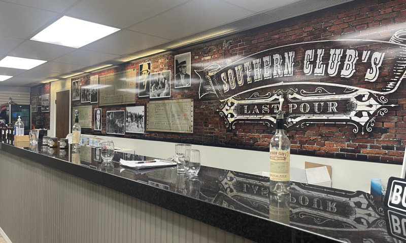 Bar with bottles and memorabilia with a Southern Club sign behind it.