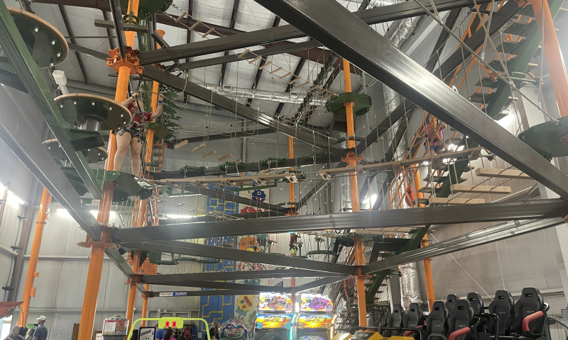 Looking up at two-story obstacle course with rope bridges and platforms.