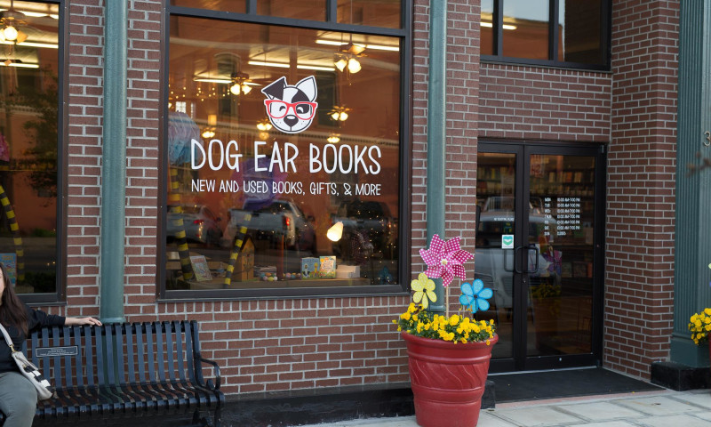Store front with flower pot and window sign reading, Dog Ear Books.