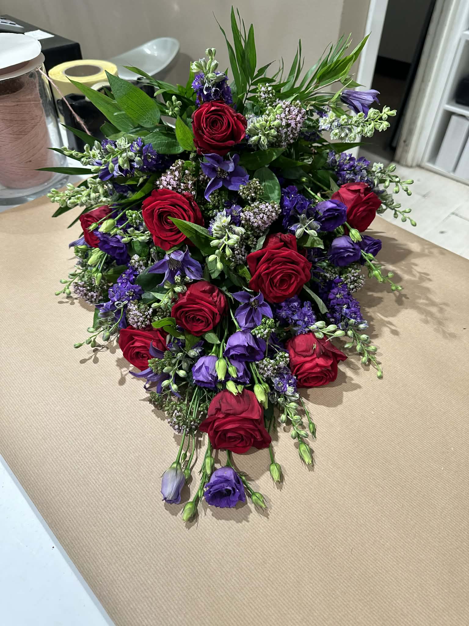 Bårebuket med røde roser og lilla blomster