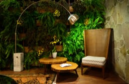 vista interna Cadeira alta com luninária e plantas ao fundo.