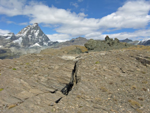 19. Niveaux fracturés des schistes lustrés vers le bord du replat de la Motte. Au second plan, sur la droite, un noyau noir de serpentinite. Au fond le Cervin.