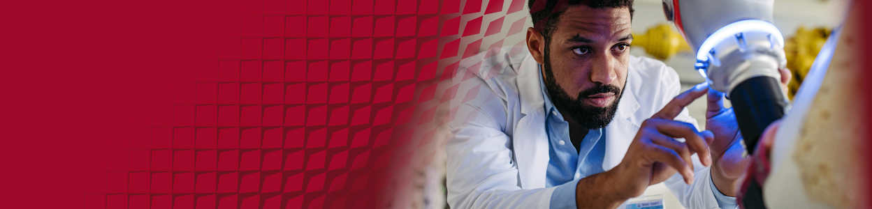 Engineer inspecting and adjusting a surgical robot in a laboratory setting.