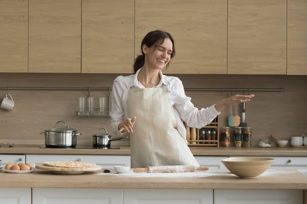 Happy woman dancing in kitchen while making pizza