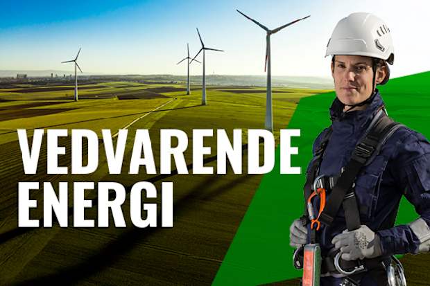 Kvinde med hjelm og faldsikringsudstyr foran en række vindmøller.