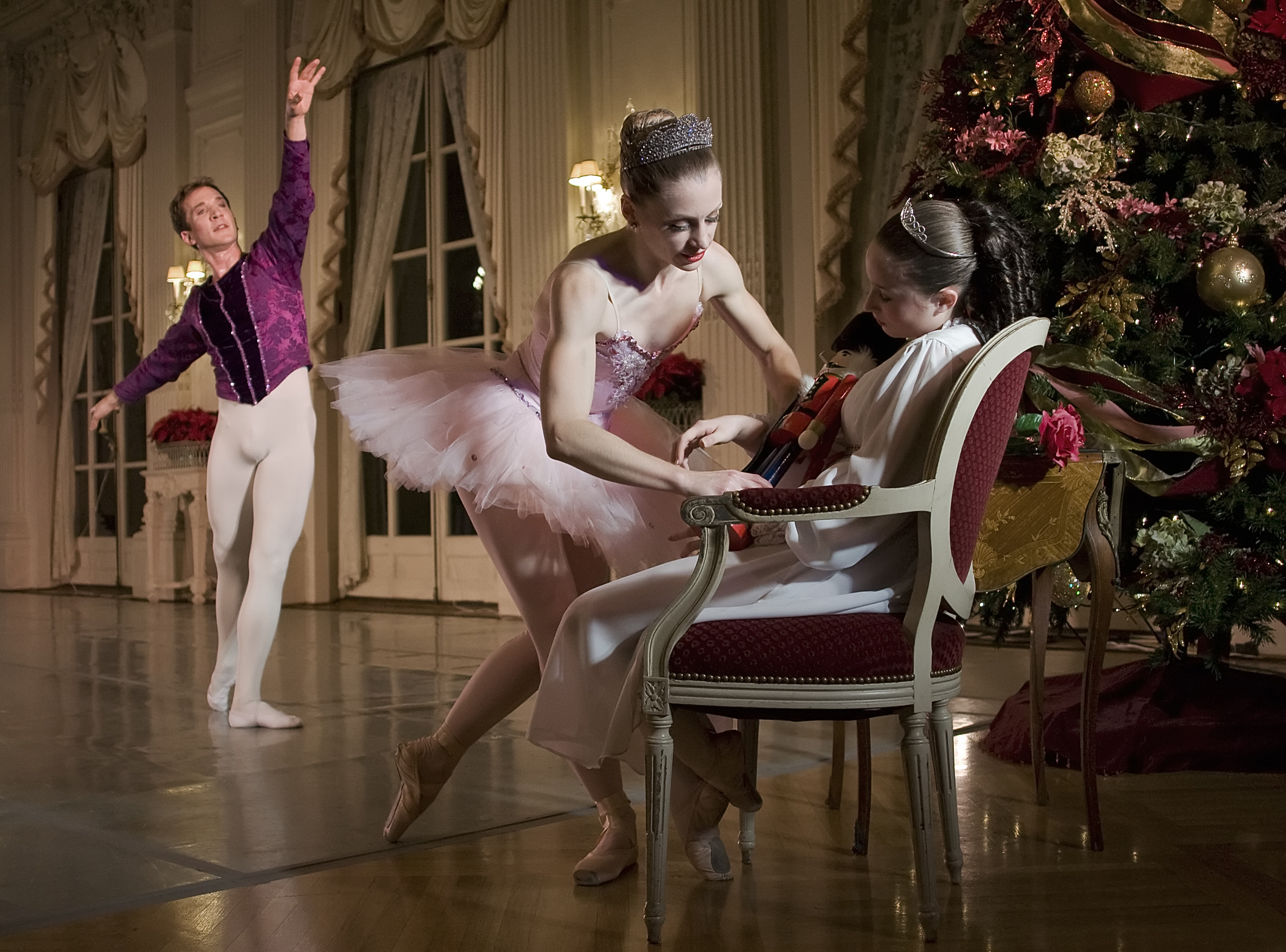 Gregg Saulnier as the Cavalier watches as Danielle Genest as the Sugarplum Fairy place the Nutcracker on the lap of the sleeping Tess (Hayden Maguire) in Island Moving Co.'s Newport Nutcracker at Rosecliff.