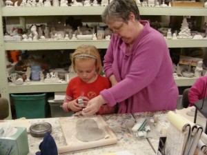 Sally patiently teaches a young artist how to make a pumpkin at Sally Ann's Ceramics.