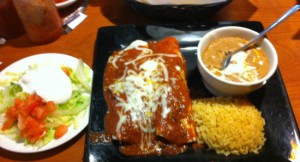 Enchiladas filled with ground beef and served with refried beans and rice.