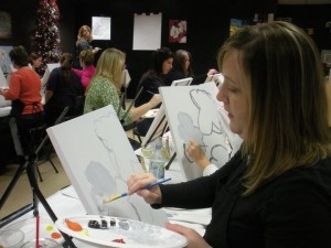 My wife working on one of her many Wine & Canvas paintings.