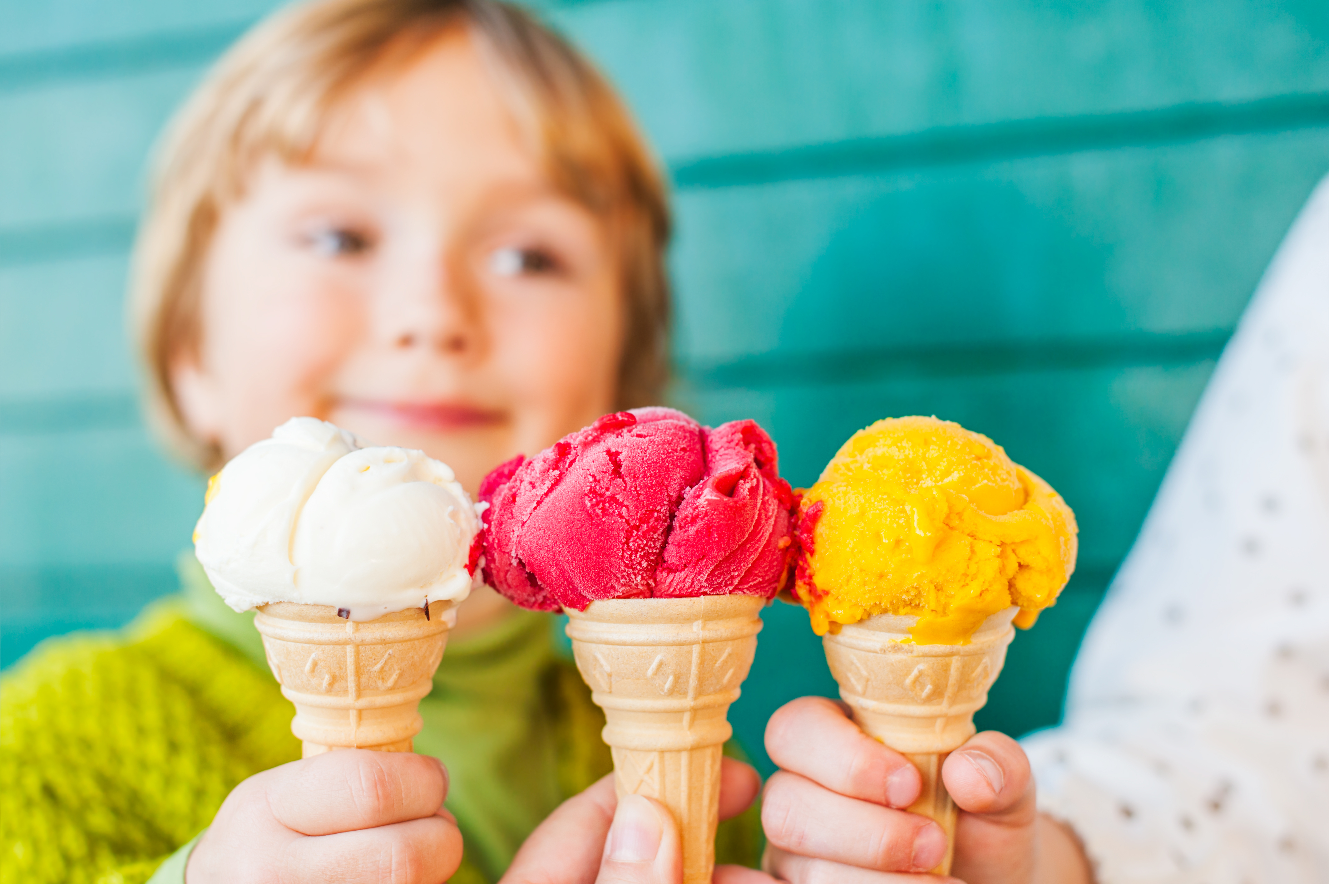 Child behind close up of three ice cream cones