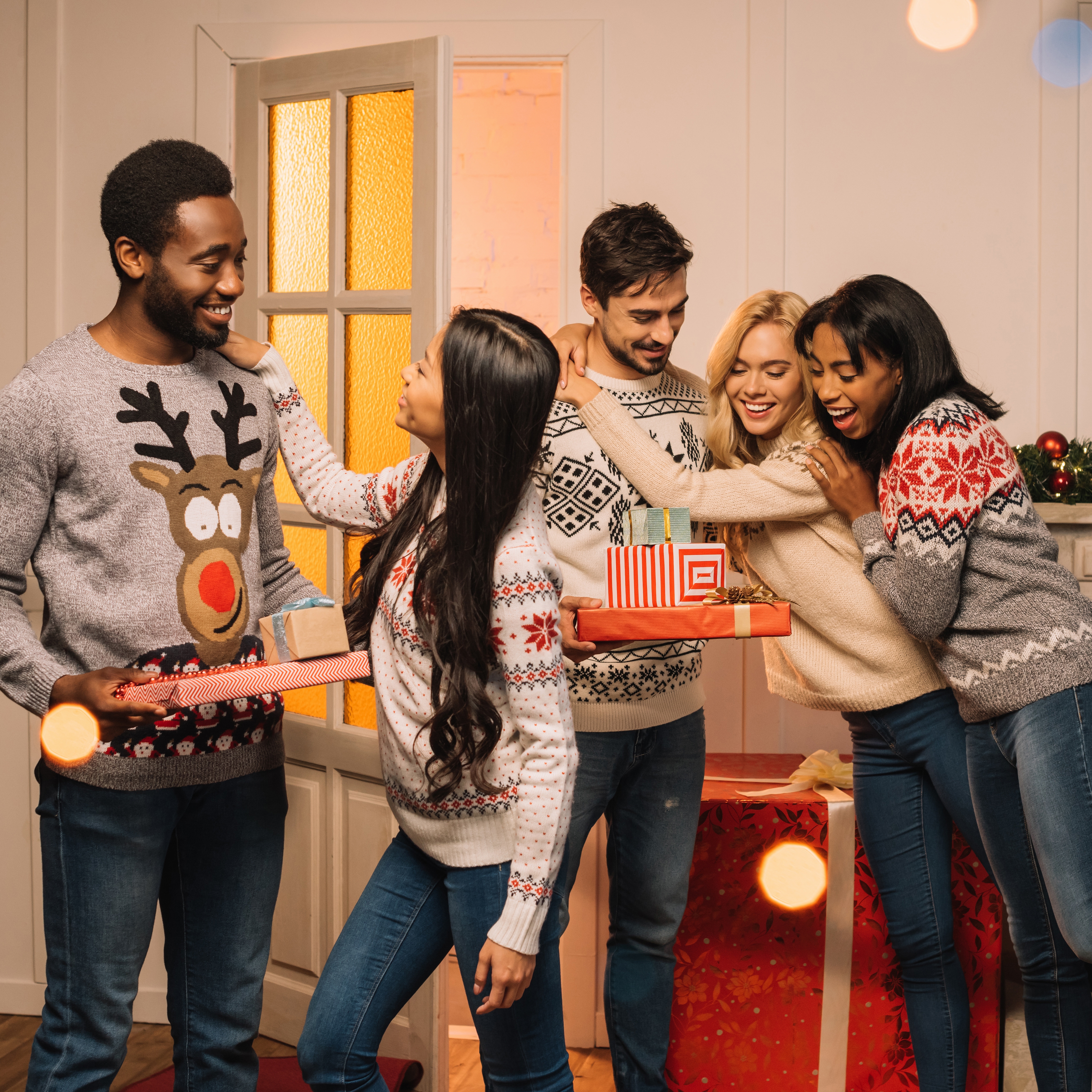 Several friends in tacky holiday sweaters smiling and hugging