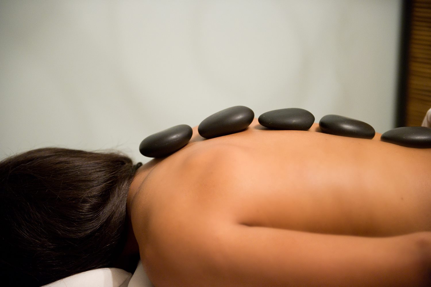 Woman with hot stones along spine at the River Spa in Lafayette