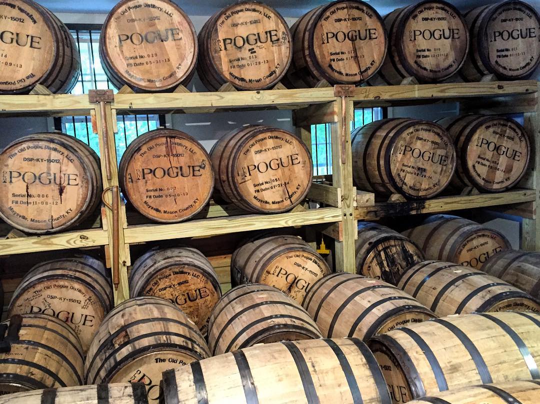 Racks of bourbon barrels in a rickhouse, marked with the name of Old Pogue Distillery