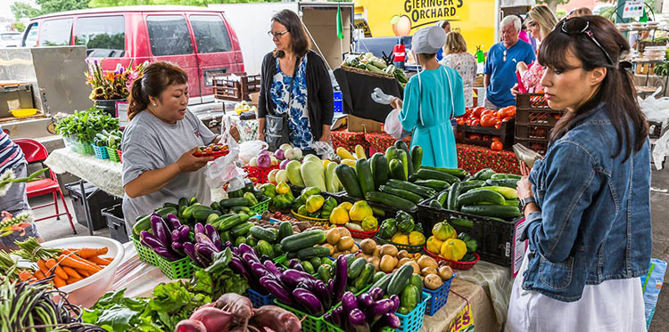Shoppers examine vegetables at the Open Air Farmers Market in Overland Park
