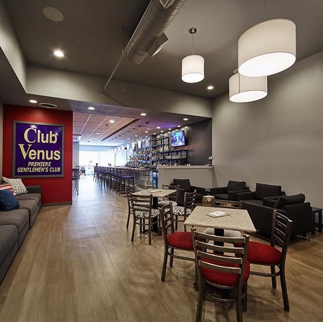 Inside The Globe Covington bar, with long modern bar, wood floors, red-seat chairs, and the old blue Club Venus sign on the wall