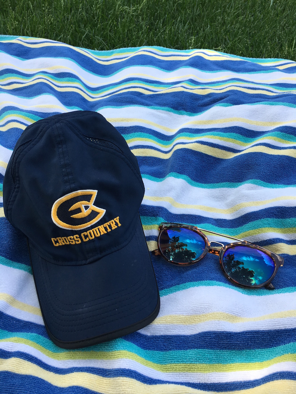 Cross Country hat and sunglasses on beach towel for day trip to Big Falls