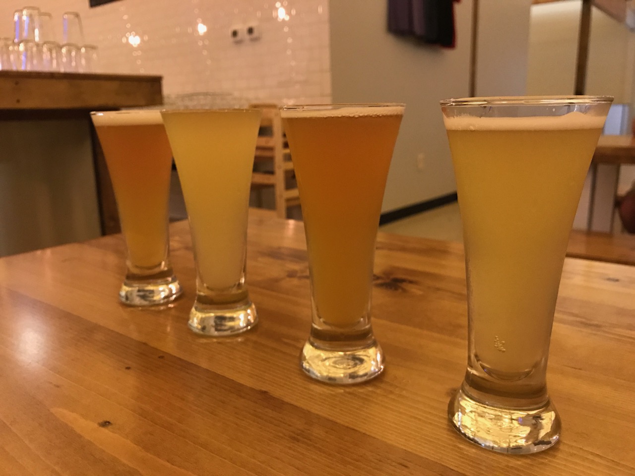 Flight of four different beers on table in minimalist, modern Random Precision taproom