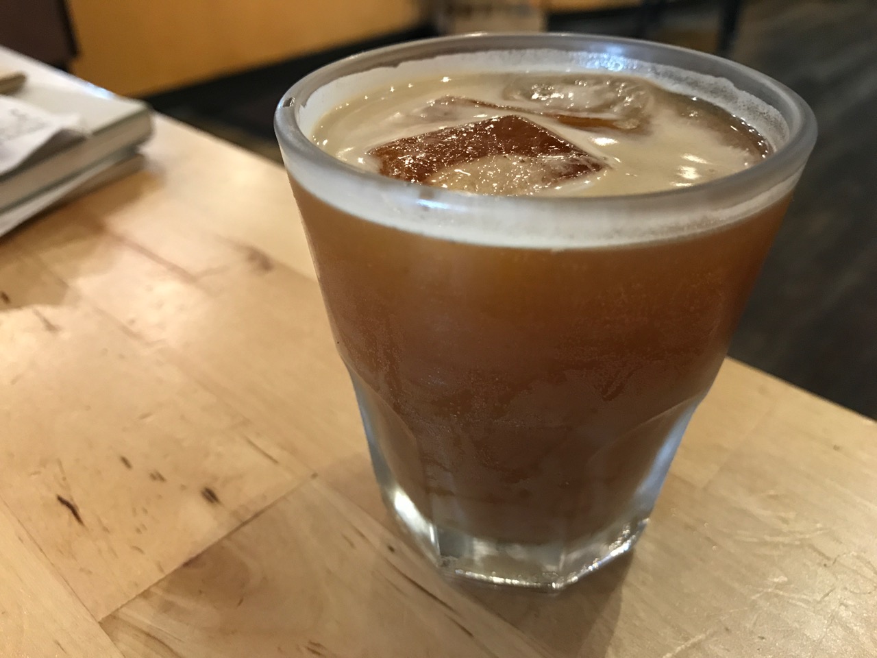 Fizzy iced coffee beverage in glass on wooden table