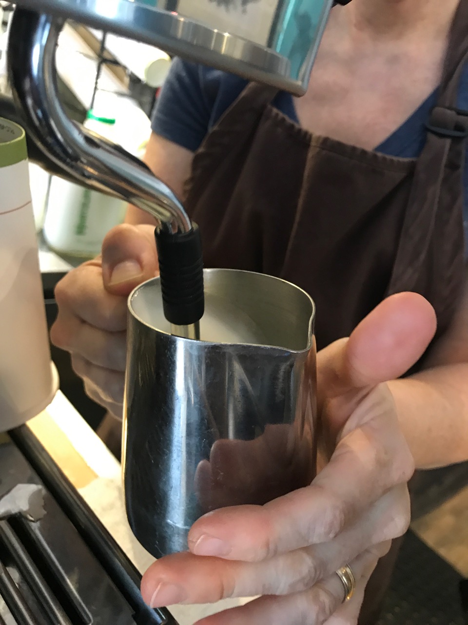 Close-up of barista's hands holding mug at coffee machine