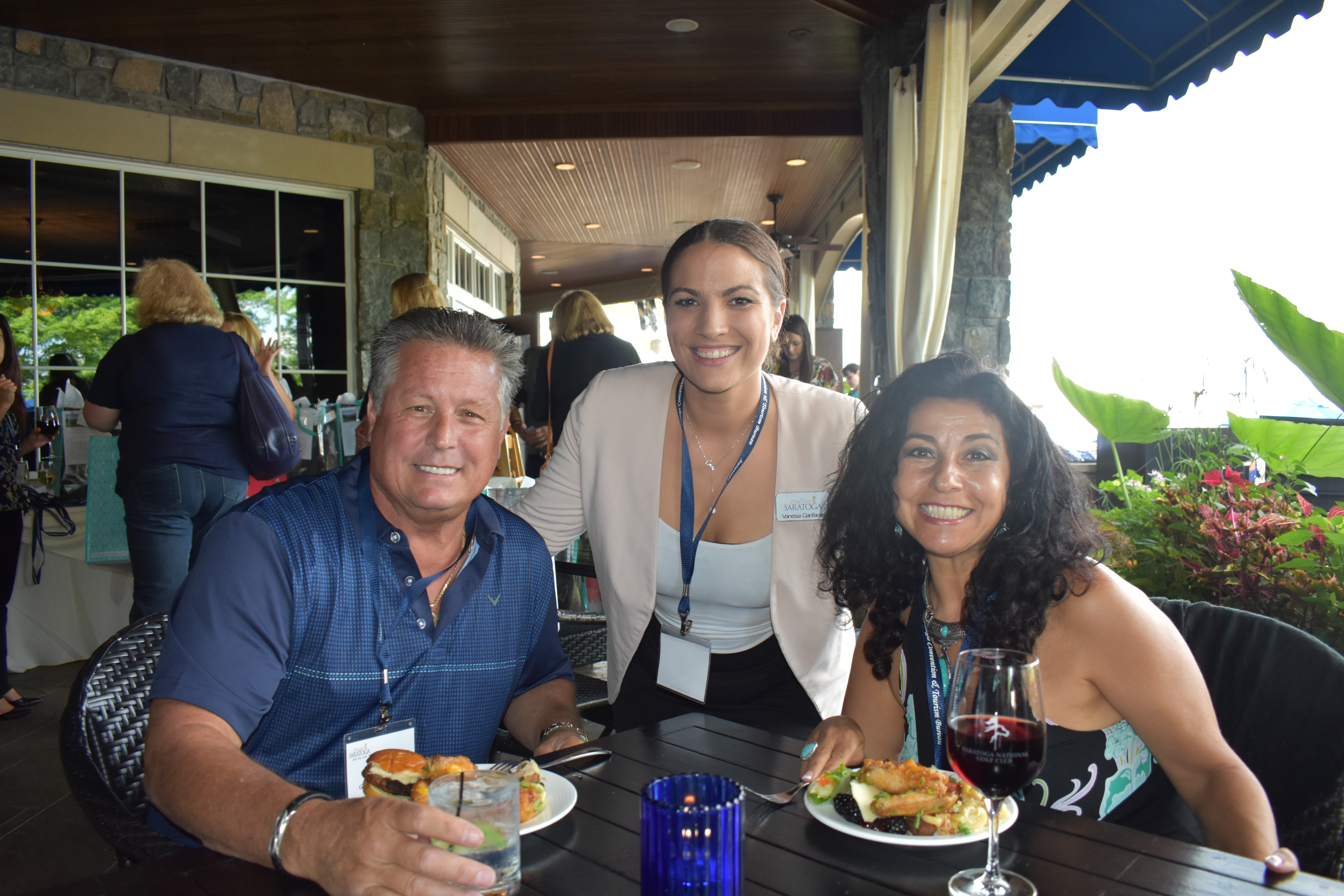Three people smiling together at a networking event in Saratoga National