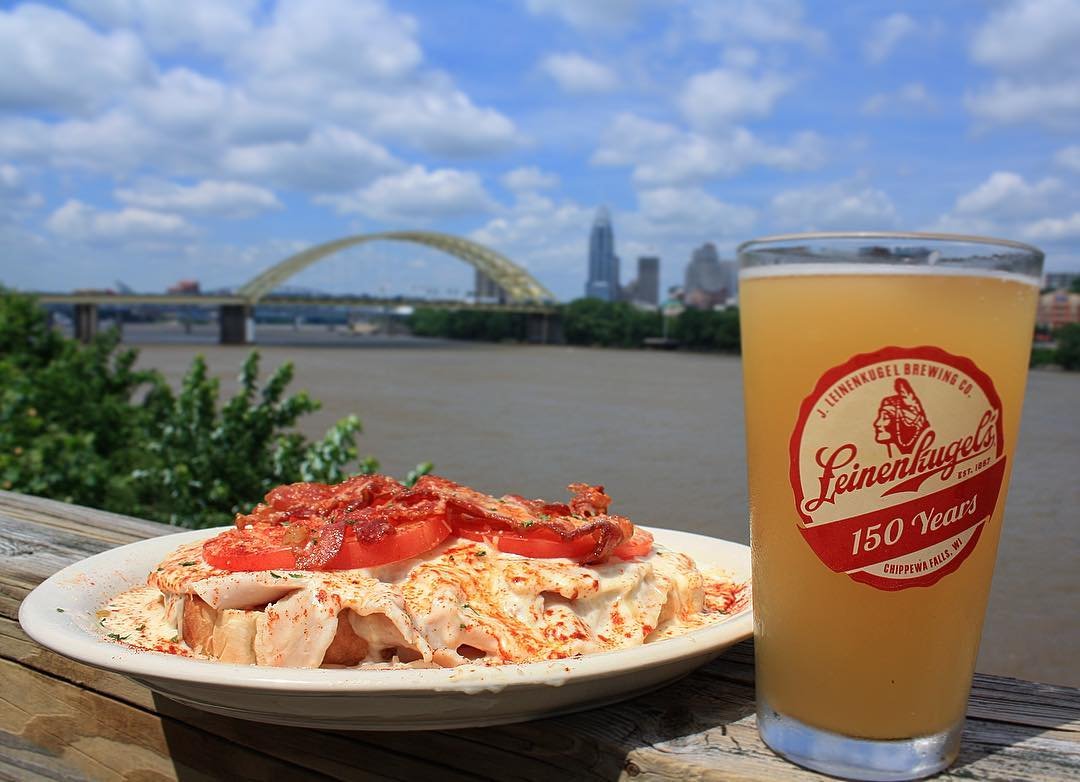 Plate of food and a beer in foreground on deck rail of Buckhead restaurant with view of Cincinnati