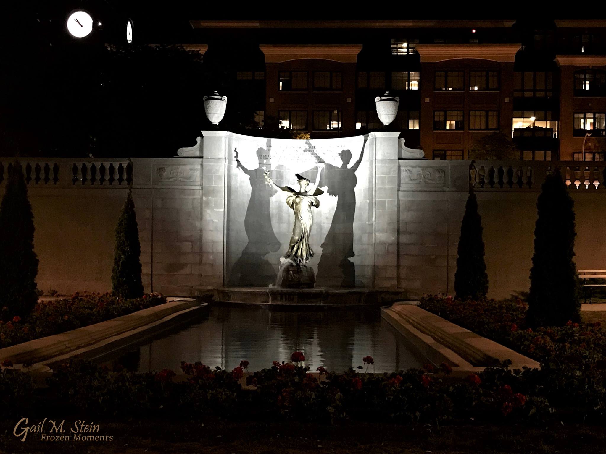 Spirit of Life and two large shadows, lit up at night