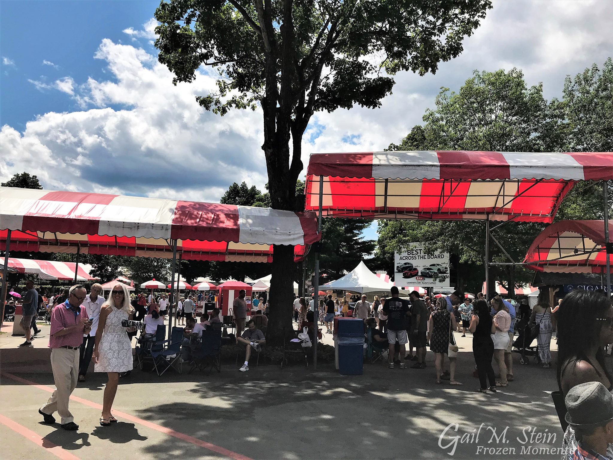 Crowd of people walking under red and white awnings at the track.