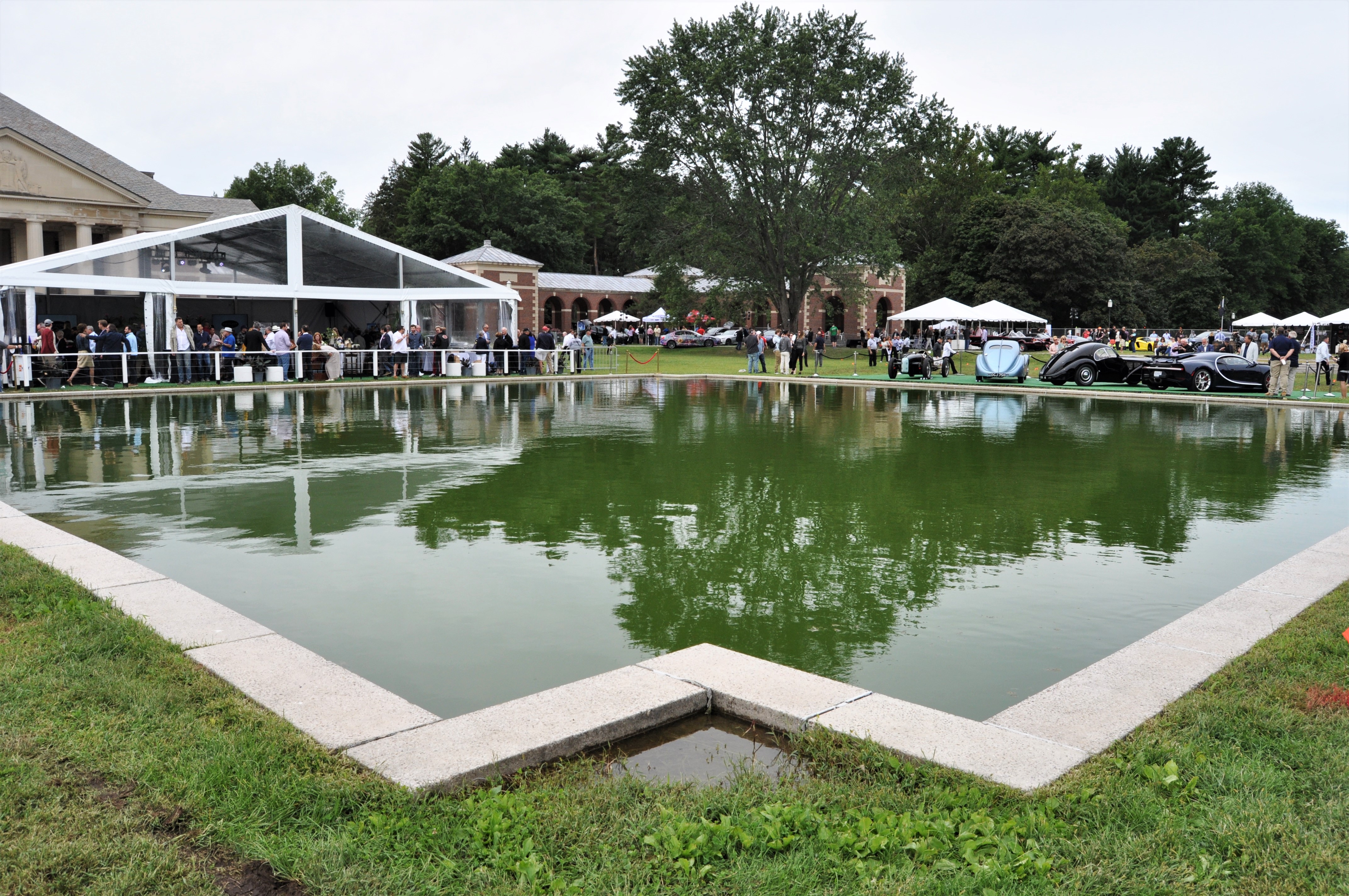 Full shot of reflecting pool with cars at far end