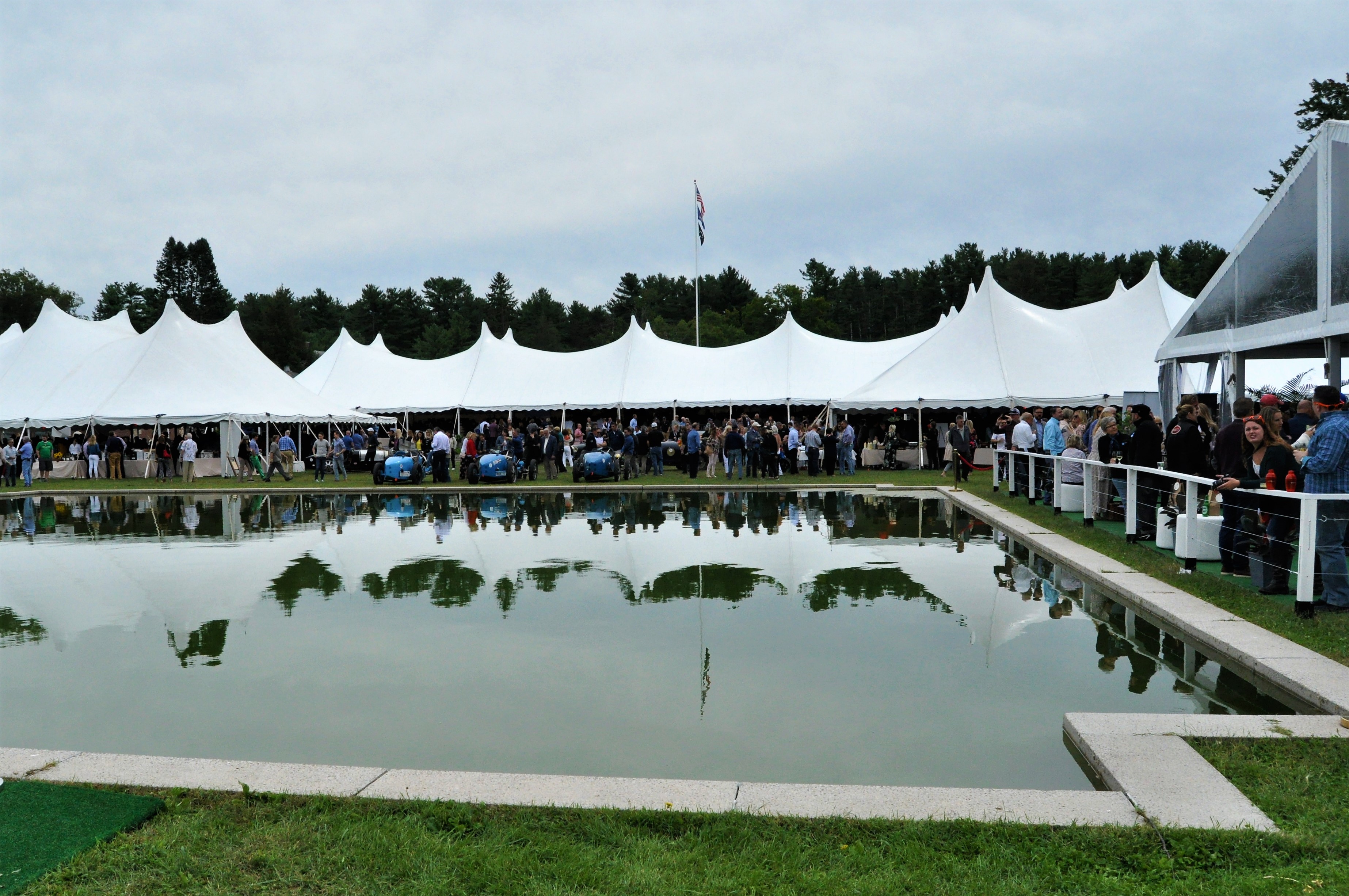 Tents reflecting on pool with cars