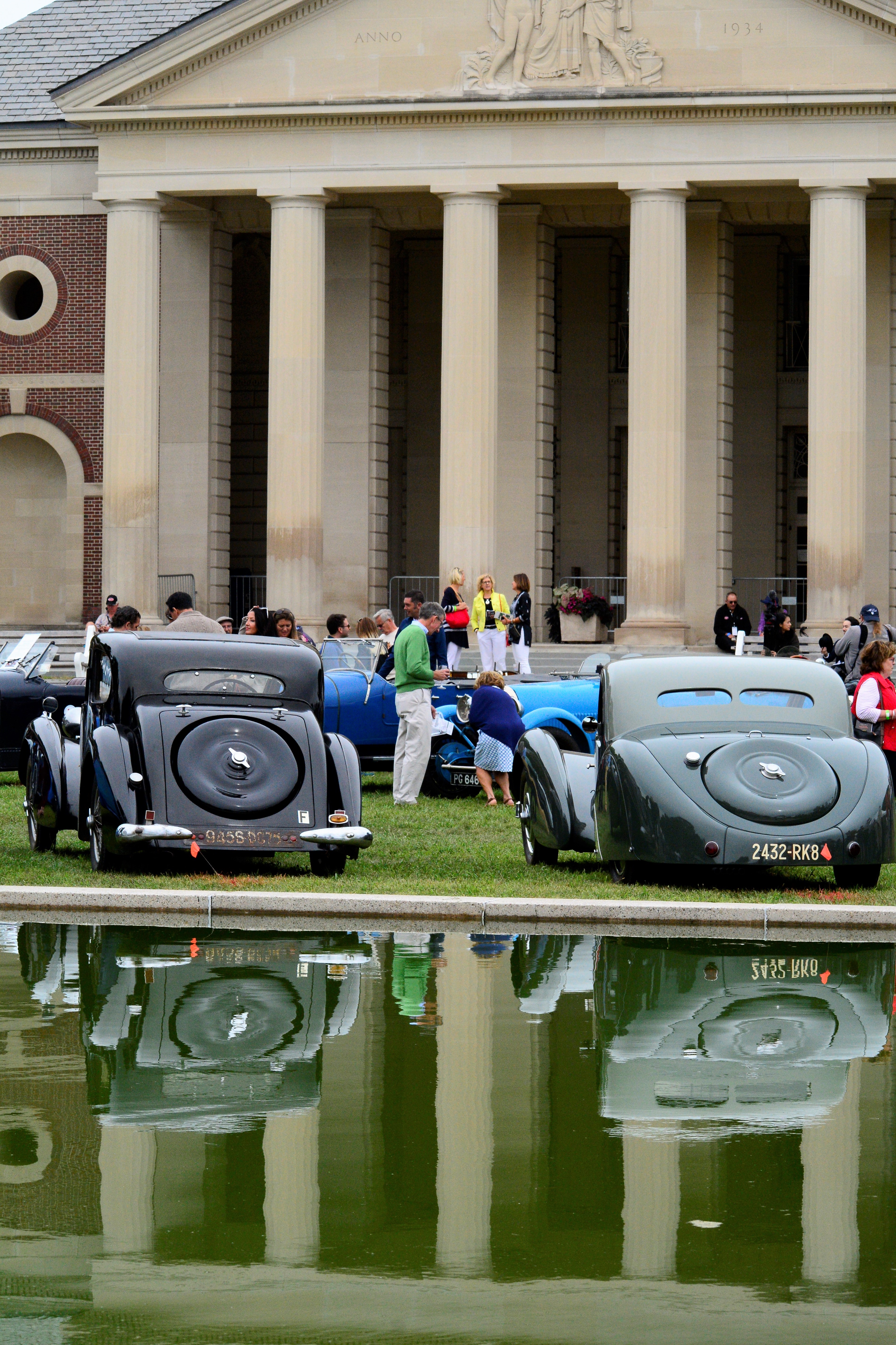 Backs of two cars reflected on water