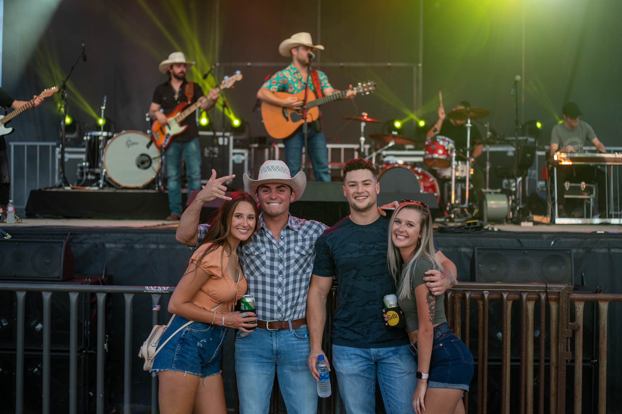 4 young people posing for photo in front of live music stage