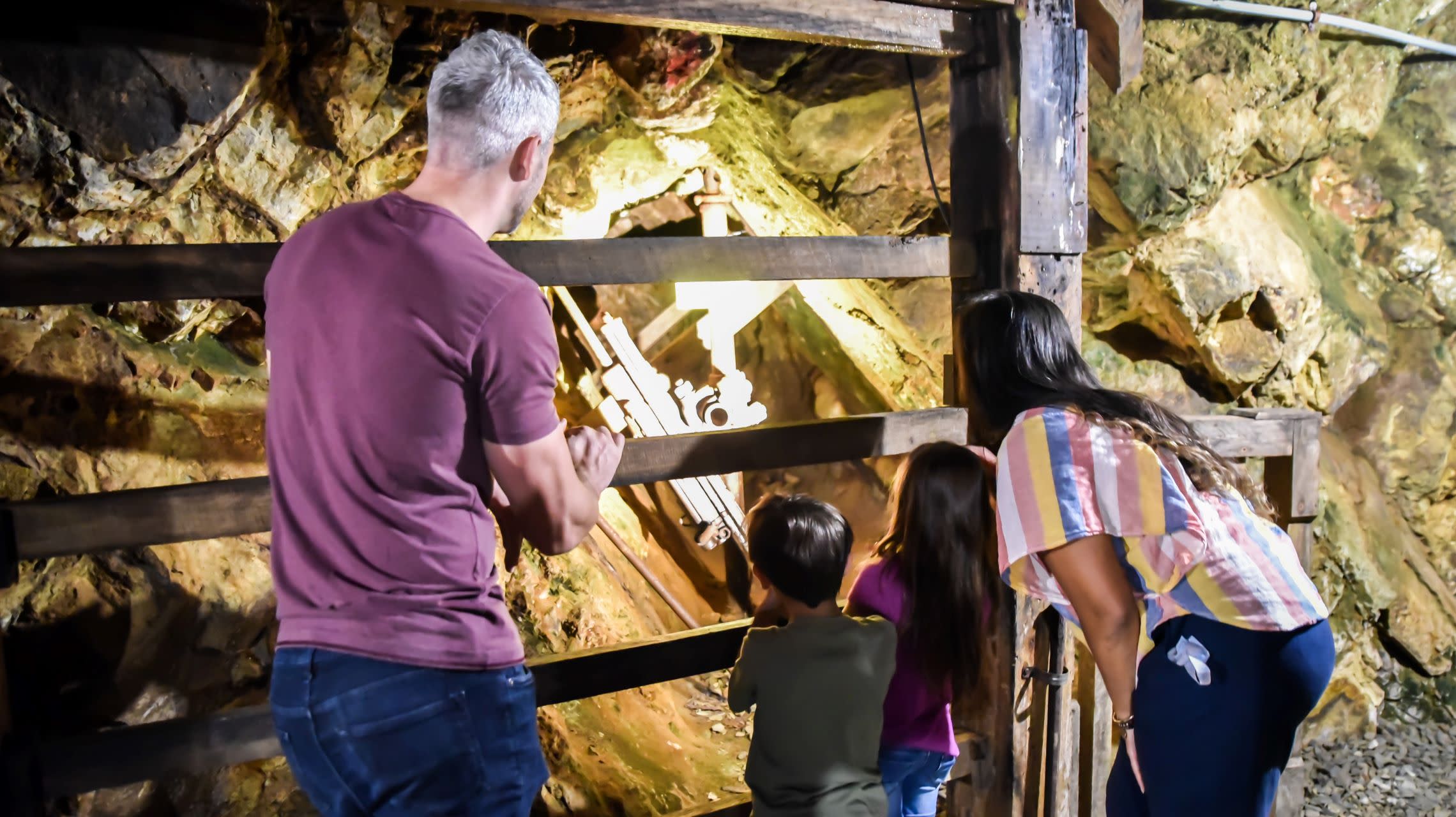 family looking at exhibit inside underground gold mine tunnel