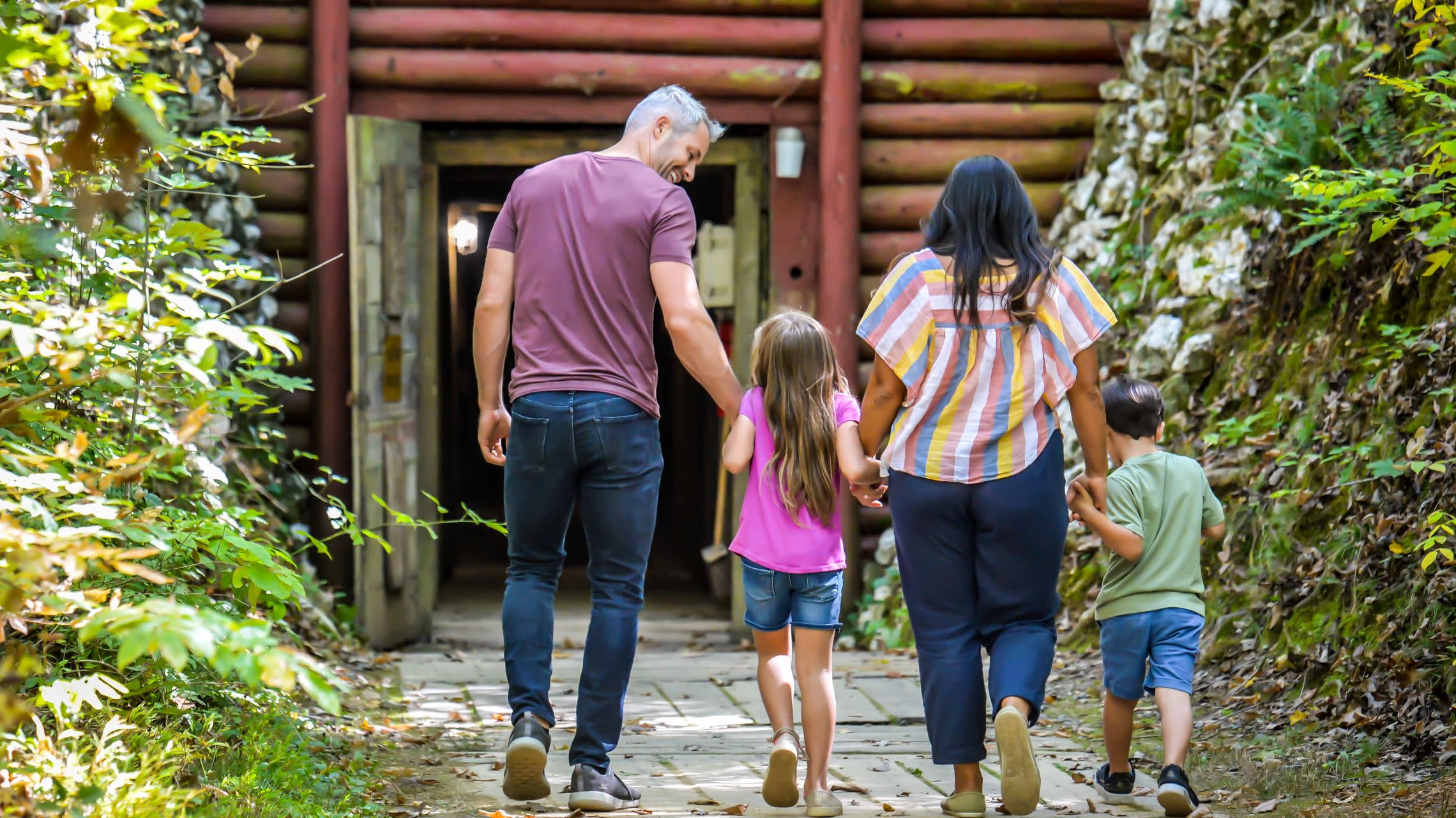 family of four walks toward the entrance of restored gold mine tunnel