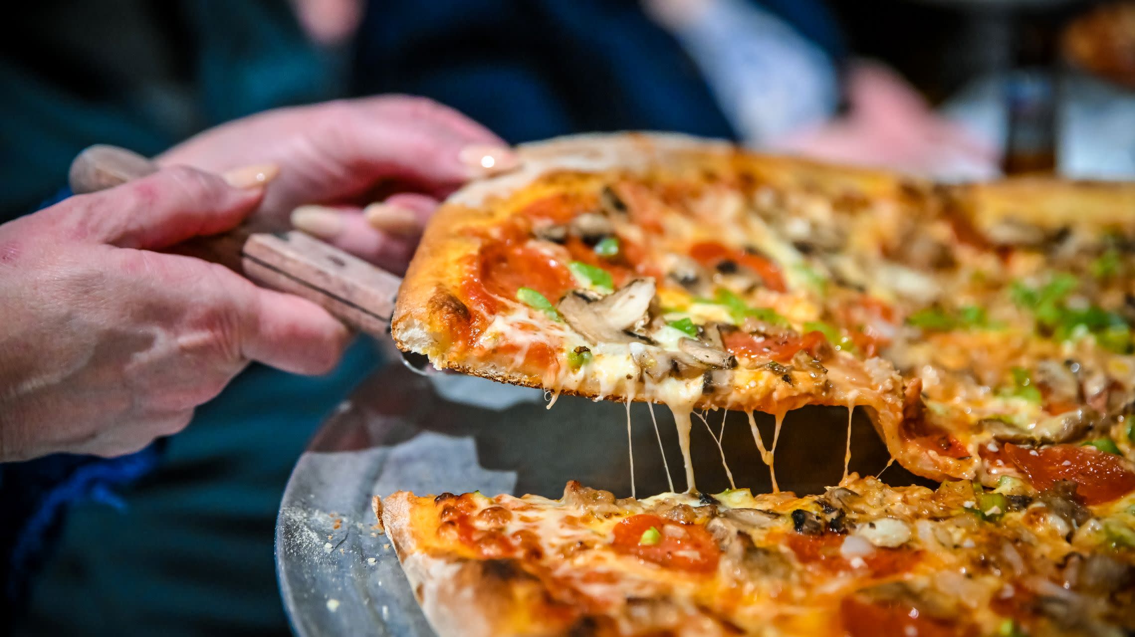 hand grabbing a slice of pizza