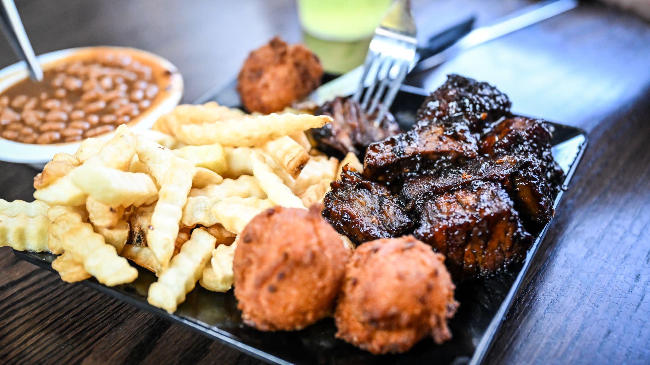 plate of barbecue brisket, fries and hush puppies