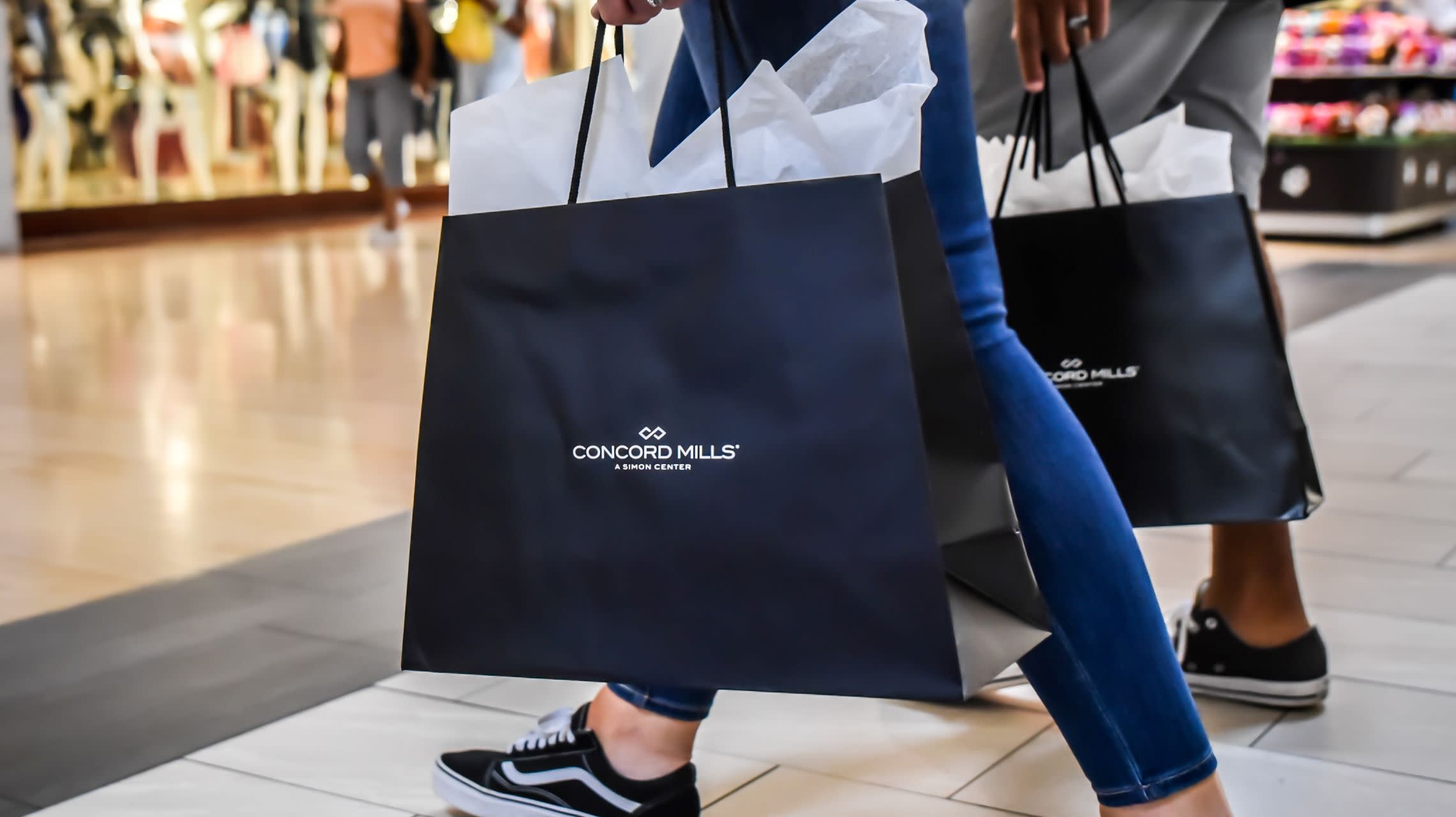 shoppers carry bags through mall