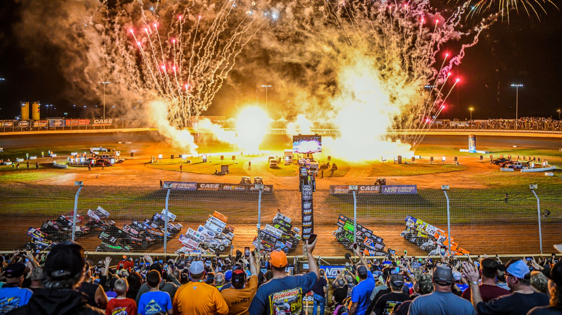 fans cheer as race cars pass on track with fireworks