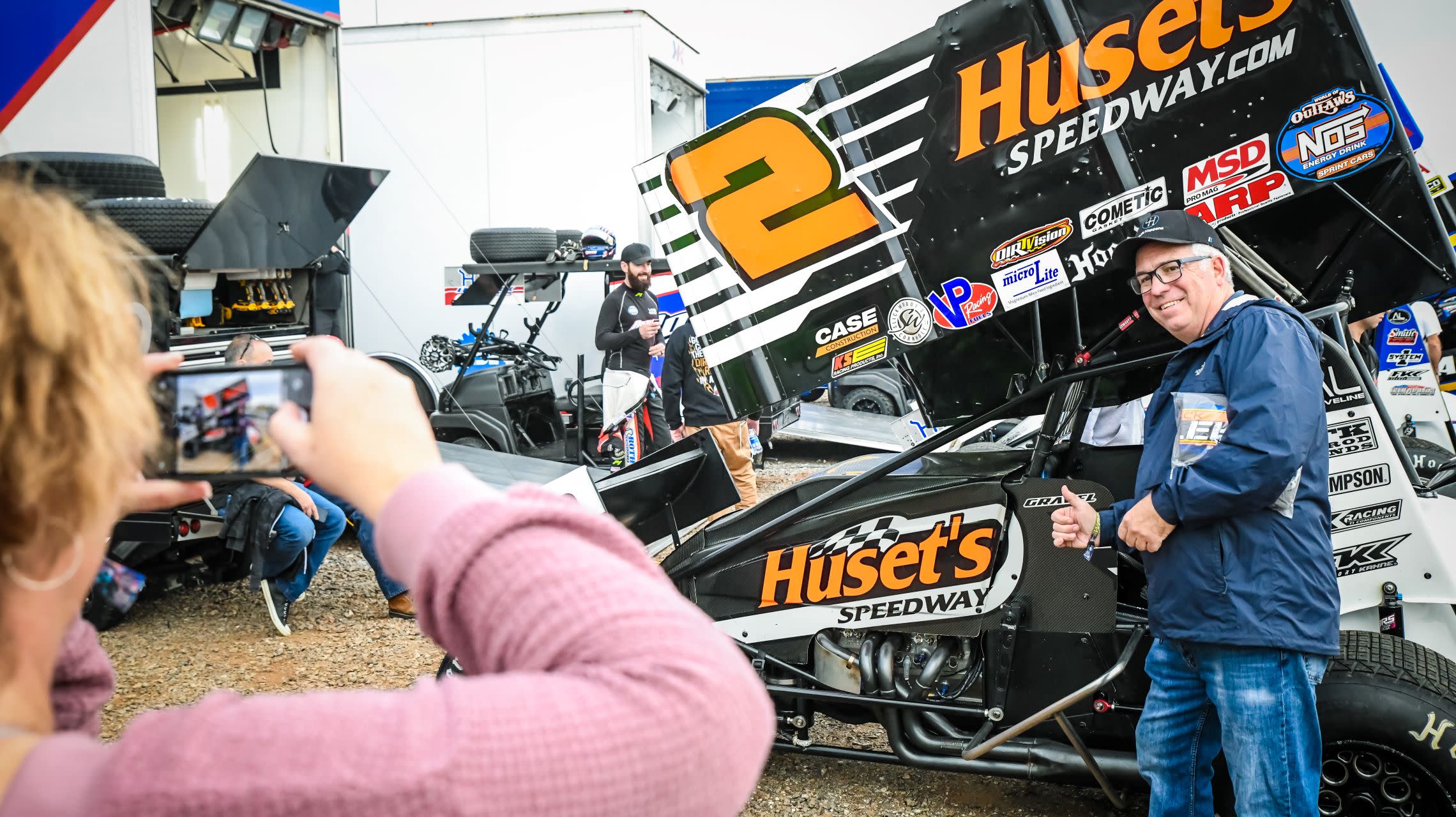 fan takes photo in front of sprint car