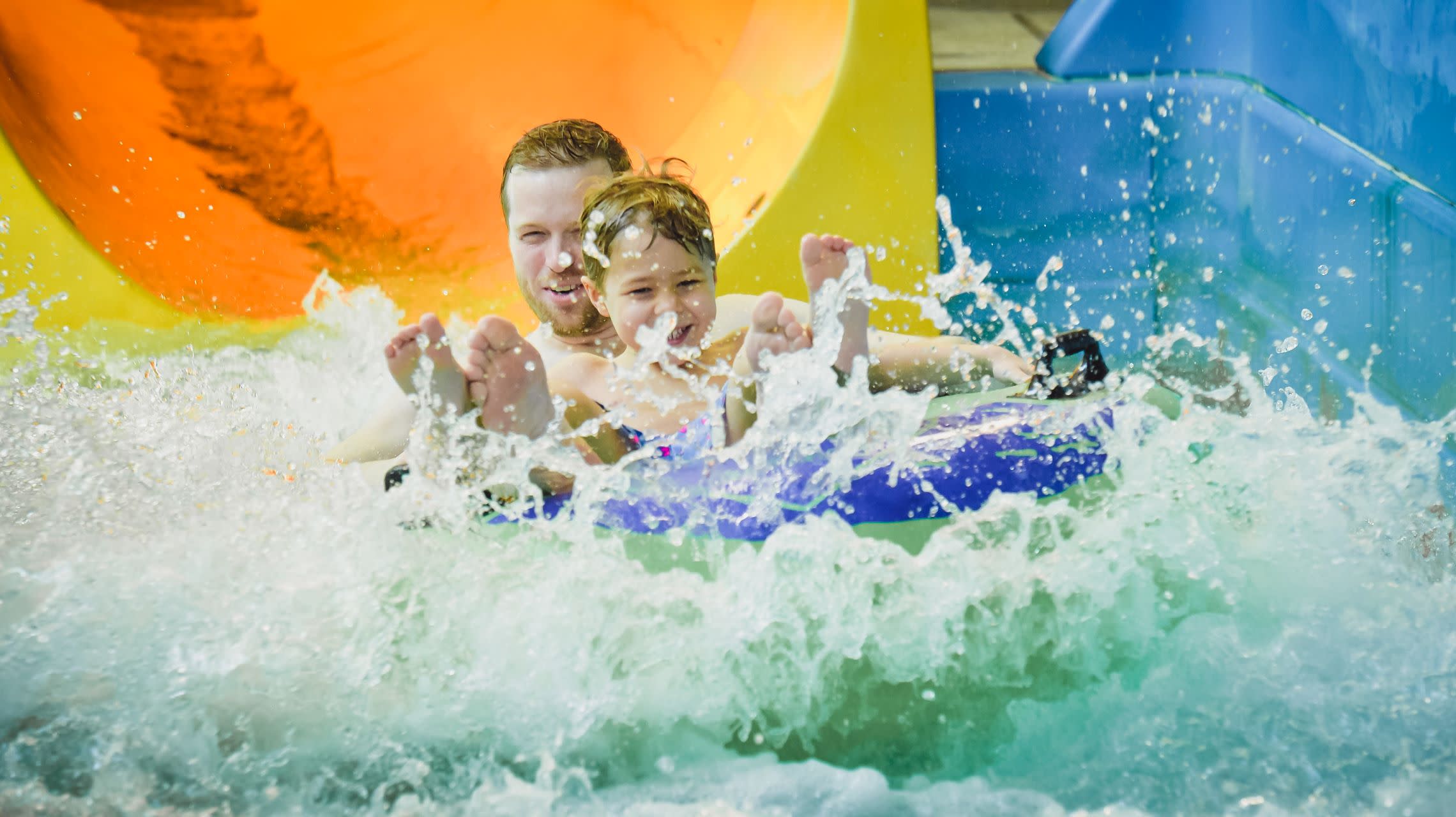 father and son splashing down waterslide