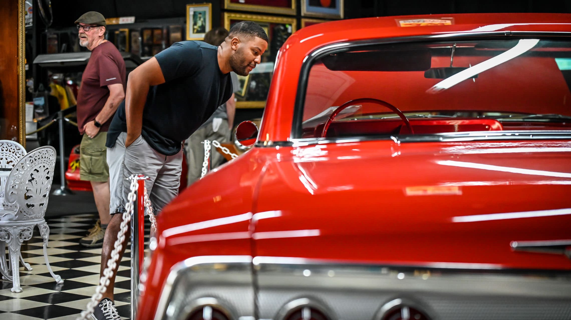 man looking inside window of classic car