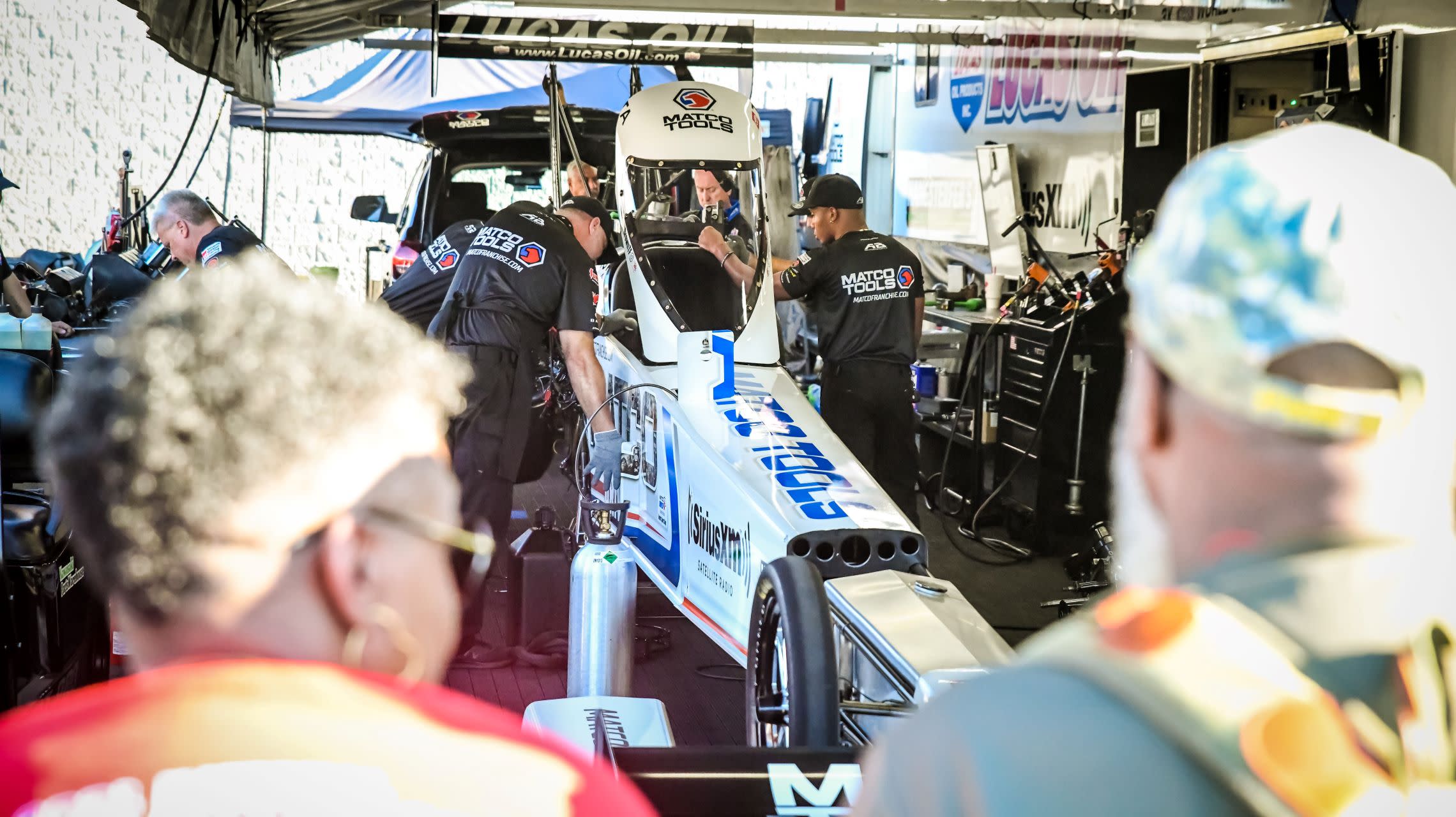 fans watch crew work on dragster