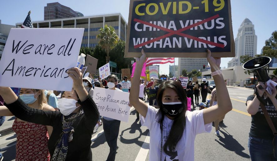 A picture of protesters in the street, wearing masks and holding signs that protest anti-asian hate in America.