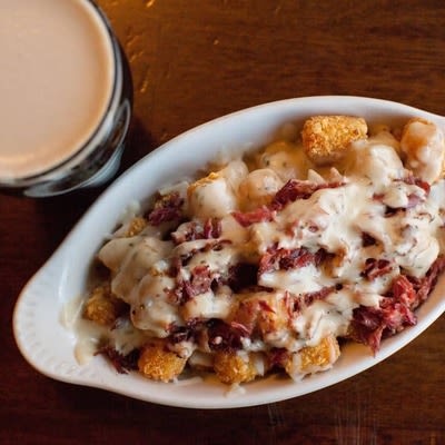 Loaded Irish Tater Tots and a glass of dark beer, top view.