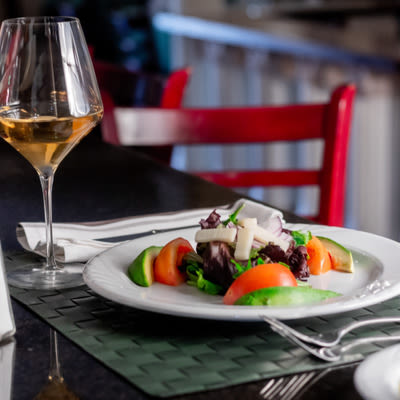 Tomato, avocado and purple lettuce salad and a glass of red wine