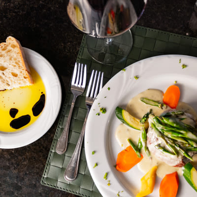 Steak with vegetables and sauce, side, utensils and a glass of red wine