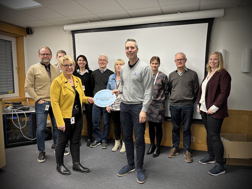 TRAFIKKSIKKER KOMMUNE: Kommunedirektør Turid Stubø Johnsen og kommuneledelsen mottar beviset på at Sarpsborg kommune er en trafikksikker kommune, fra Paal Gunnar Mathiesen i Trygg Trafikk.