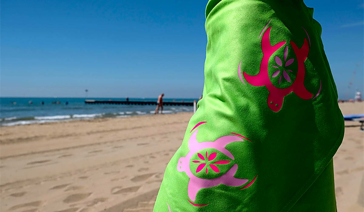 Grønt stof med lyserøde skildpadde-designs på en strand
