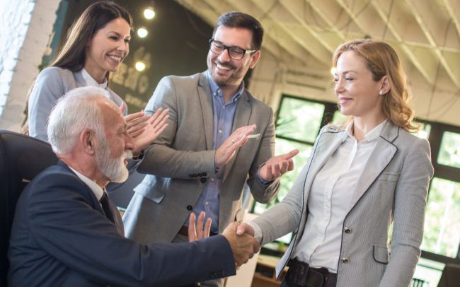 Senior boss and middle aged female employee shaking hands with c